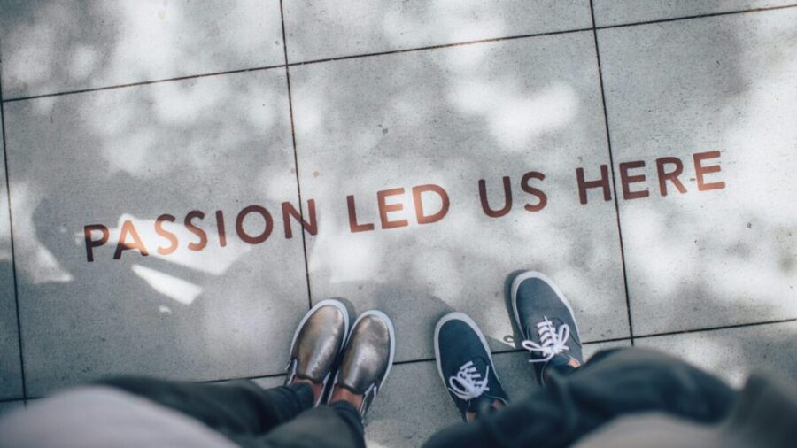 View looking down on feet approaching "passion led us here" written on ground, representing core values about us.