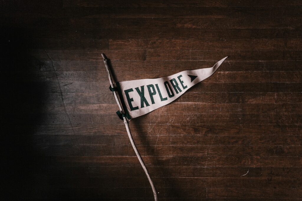Triangular flag on wooden floor that reads, "Explore," signifying Progressive Christianity's openness to deconstructing faith