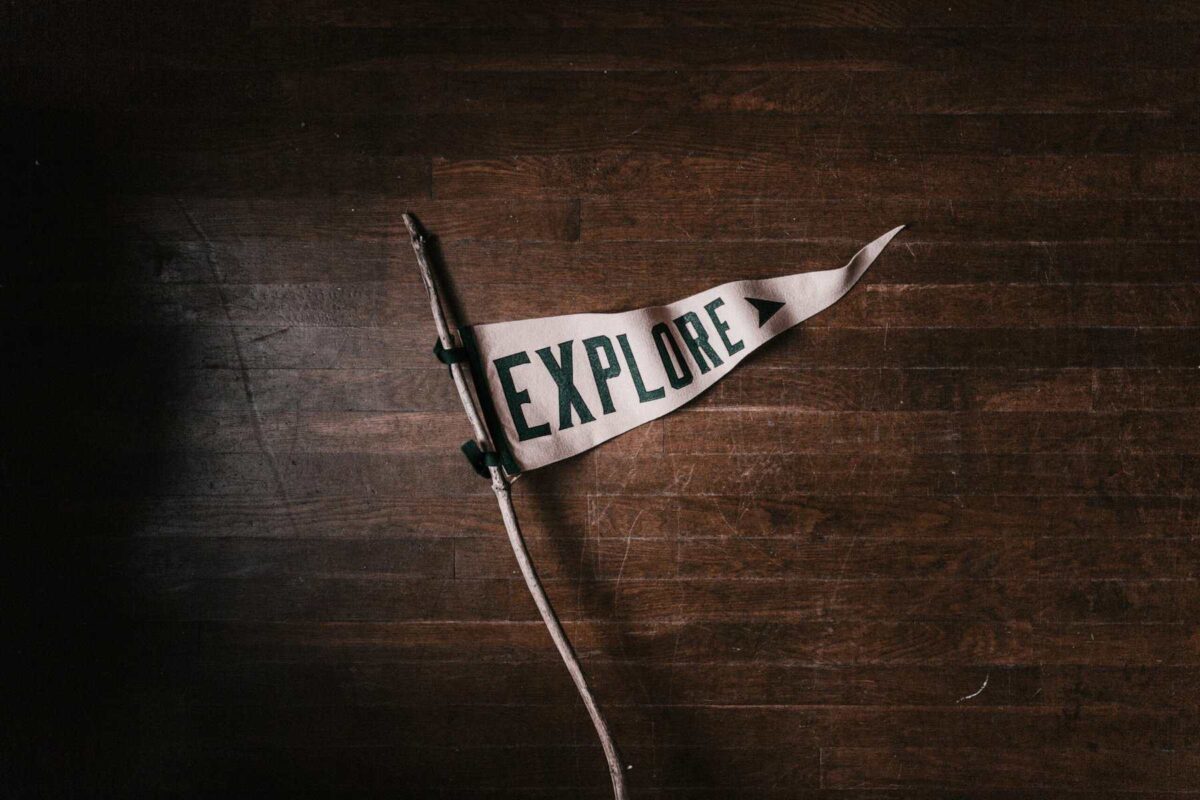 Triangular flag on wooden floor that reads, "Explore," signifying Progressive Christianity's openness to deconstructing faith